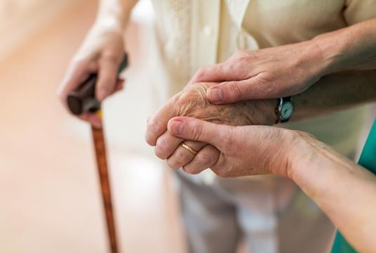 main d'une personne âgée soutenue par un soignant
